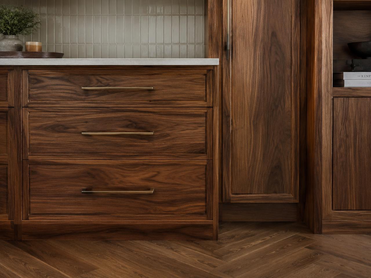 Custom walnut cabinetry with bronze pulls and herringbone floor